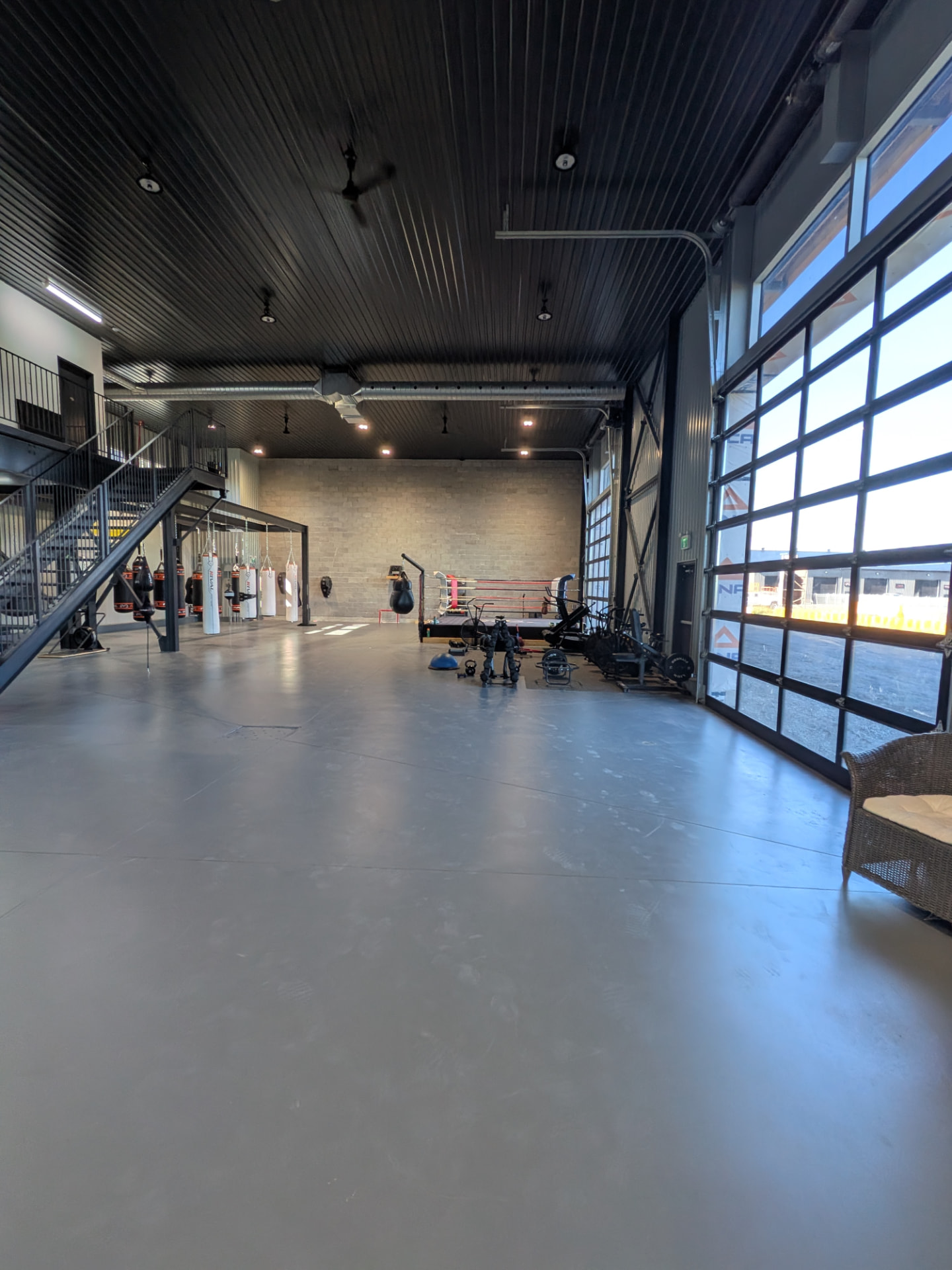 Vue d'ensemble du gym Evado avec le ring et les sacs de frappe