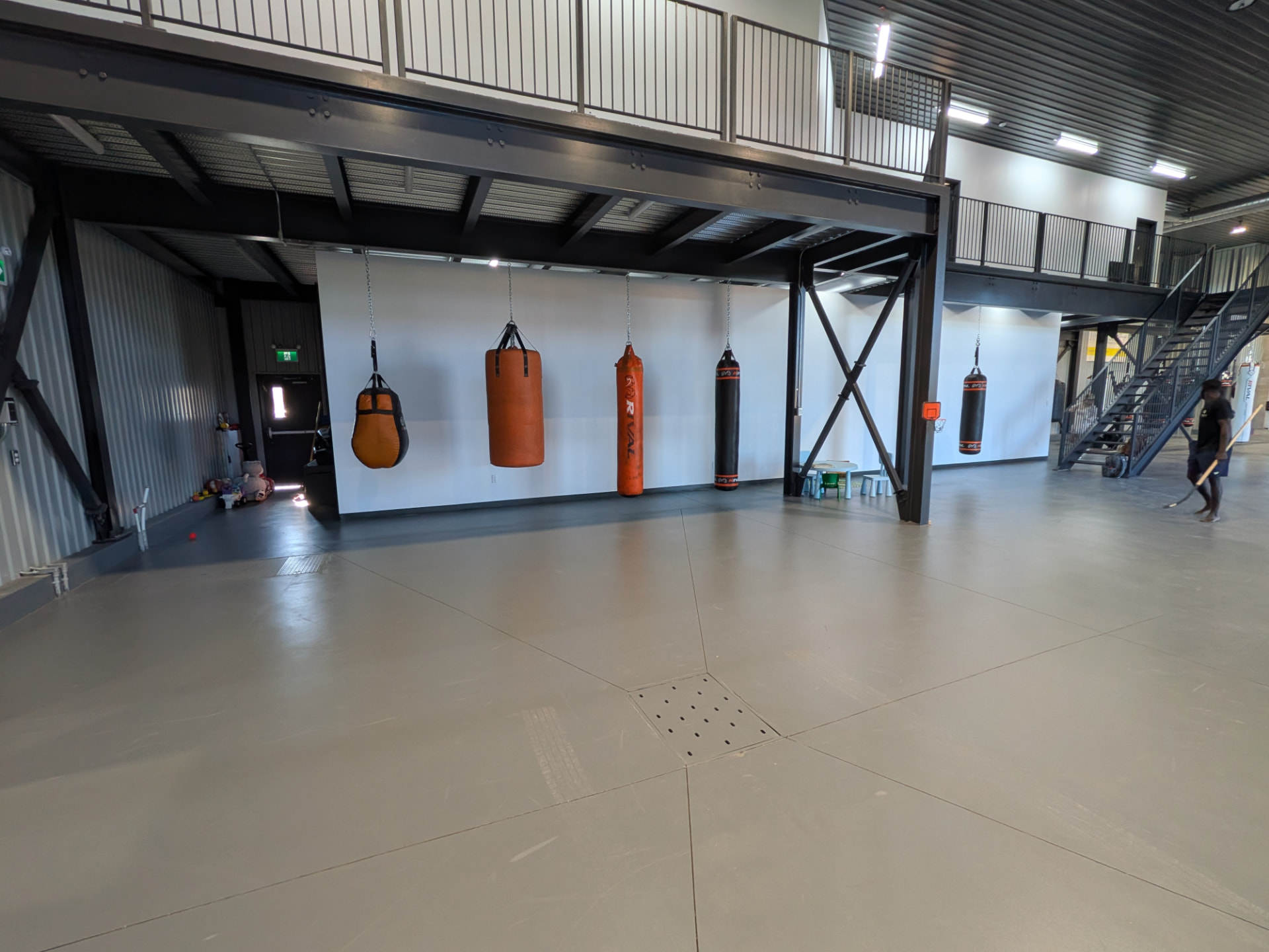 Zone d'entraînement libre avec sacs de frappe sous la mezzanine